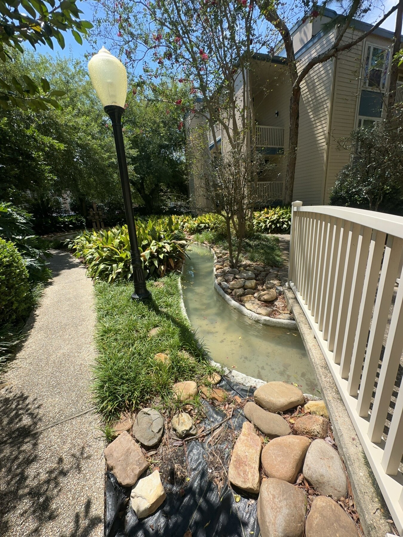 Creek water feature alongside an apartment walkway and bridge
