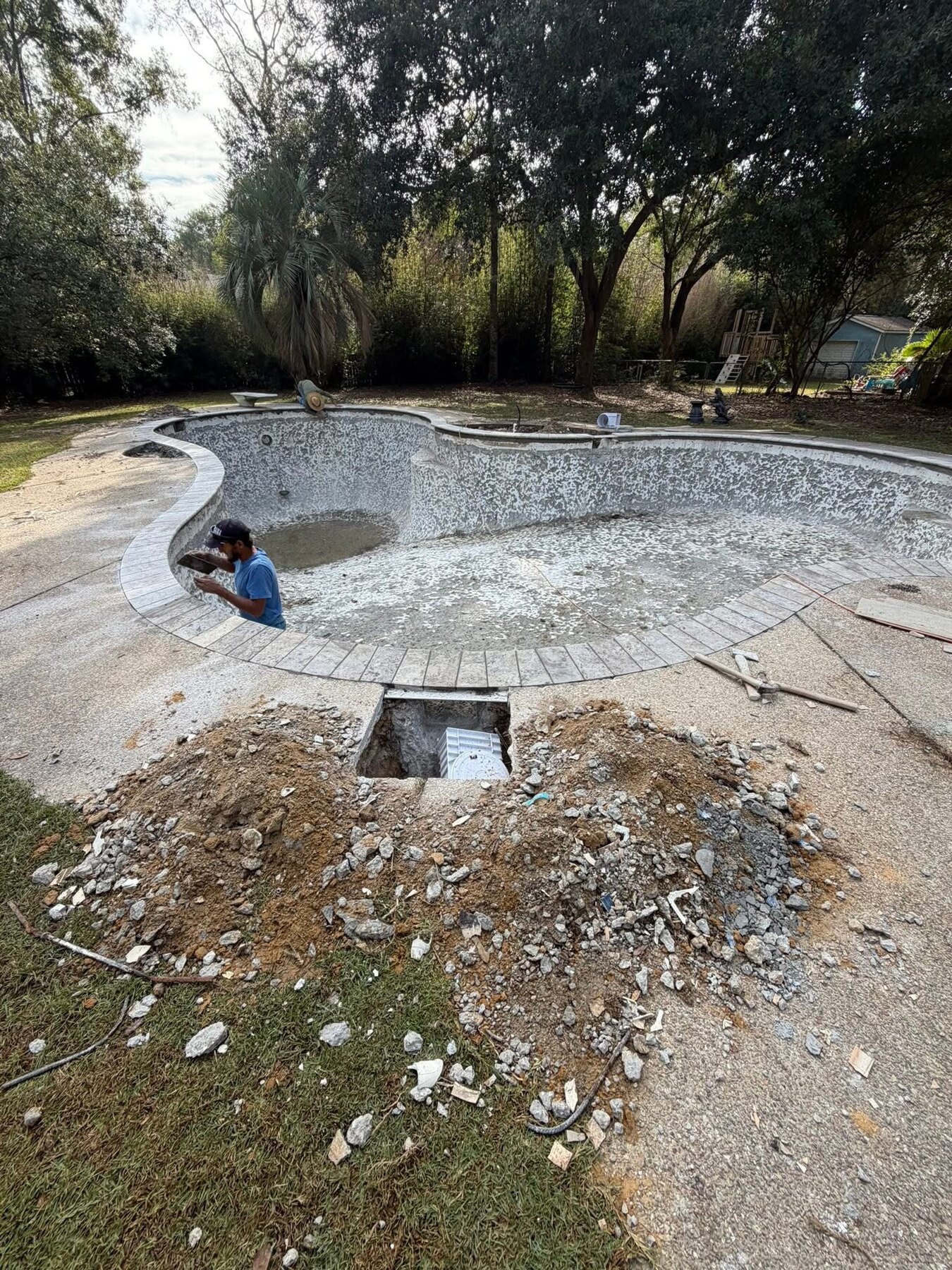 Drained pool during renovation with targeted deck access opened for repair work