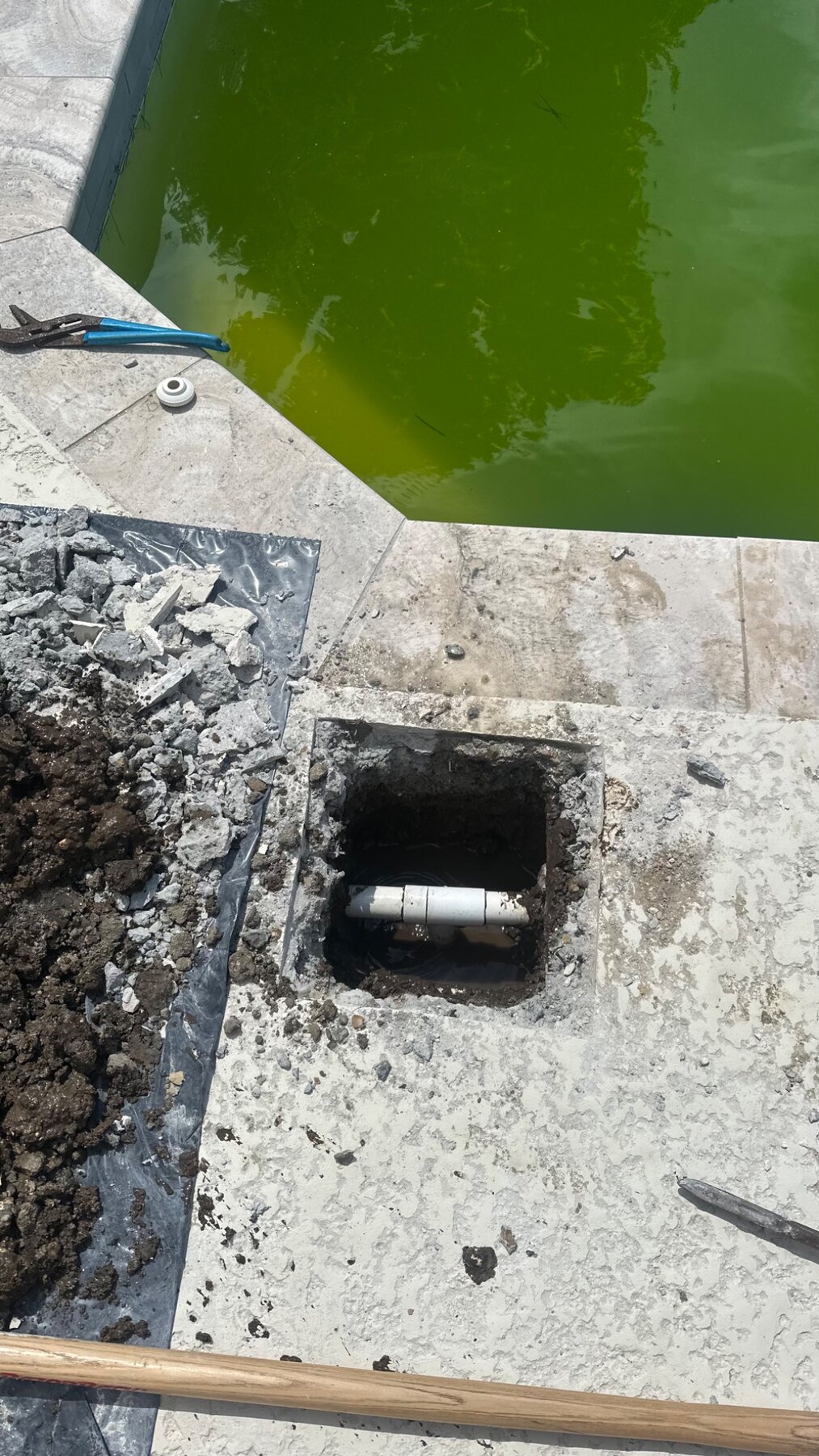 Focused concrete deck opening above the damaged pool return-line plumbing