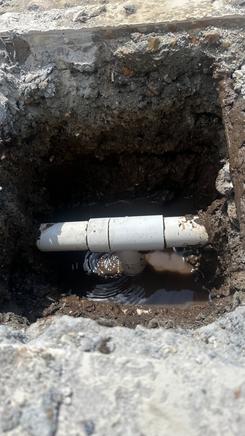 Broken pool return-line tee exposed below a targeted opening in the concrete deck